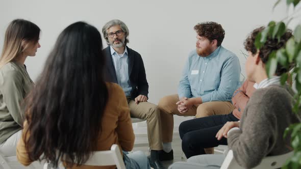 Professional Psychologist Talking to Group of Patients During Therapy Meeting in Studio alt