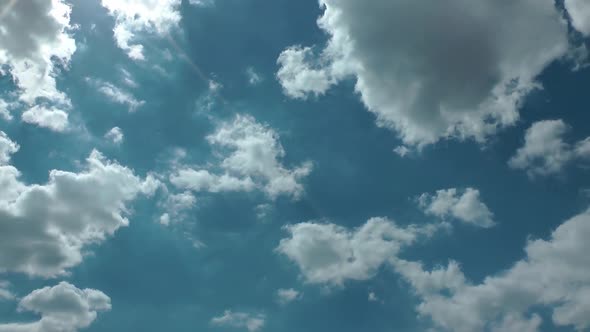 White And Dark Rain Clouds On A Blue Sky With Sun Shine Lens Flare alt