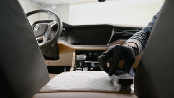 Car Detailing Service Worker Washing an Expensive Car Leather Central Panel with Brush and Foam
