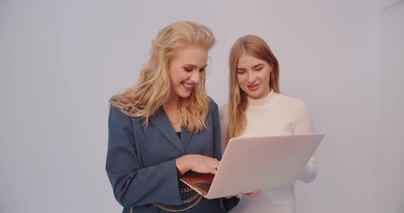 Two Girls Look At The Laptop And Smile