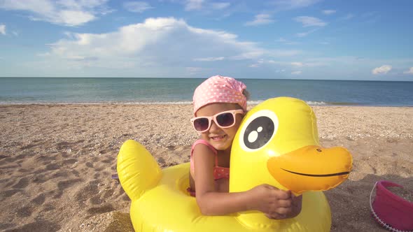 Little Baby Girl In A Bathing Suit And Sunglasses On Playing Sandy Beach On Background  Ocean alt