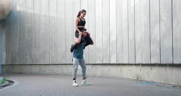 Strong Athletic Man Doing Squatting with Woman Sitting on His Shoulders alt
