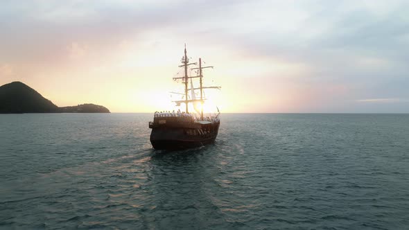 Cinematic Back View of Historic Ship Sailing Toward Scenic Pink Golden Sunset alt