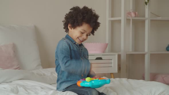 Joyful Kid Playing with Toy Steering Wheel Indoors alt
