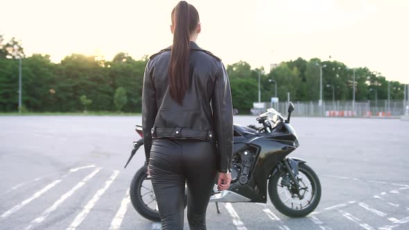 Stylish Brunette which Coming Up to Her Black Cool Motorbike and Getting on alt