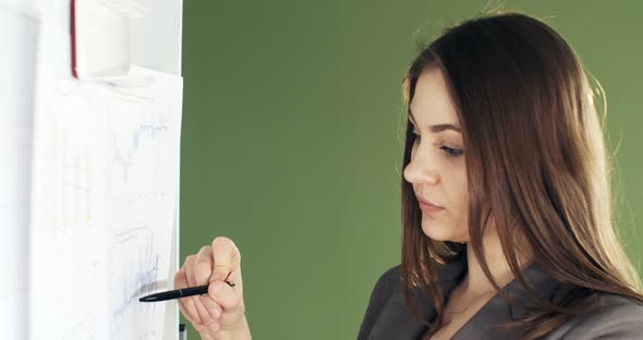 Beautiful Young Business Woman Performs Financial Calculations on Presentation Whiteboard. Working alt