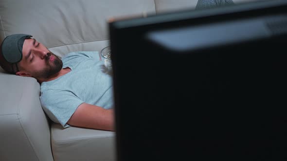 Man with Eye Sleep Mask Lying on Sofa While Watching Entertainment Movie alt