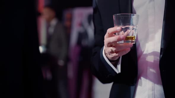 Men holding alcohol in club and talking. Gay pair on party indoors close up alt