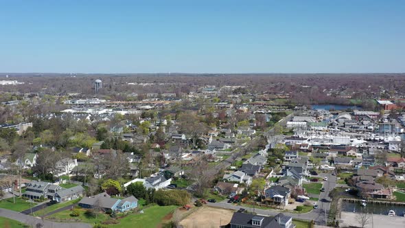 An aerial drone shot over a quiet suburban neighborhood on a sunny day on Long Island, NY.  The came alt