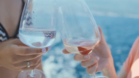 Friends raising wine glasses outdoors.  Two woman Toasting  and drinking champagne.  Slow motion. alt