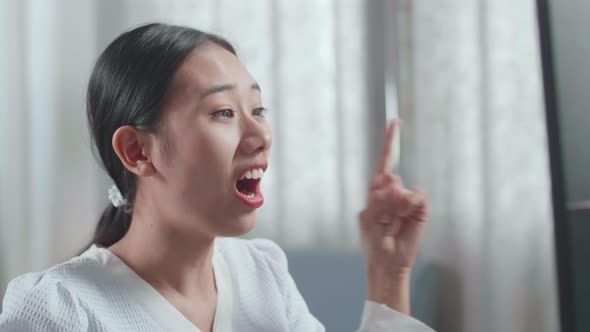 Close Up Of Asian Woman Engineer With The House Model Thinking Then Raising Index Finger alt
