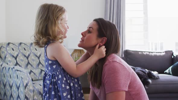 Caucasian mother and daughter having fun talking in living room alt