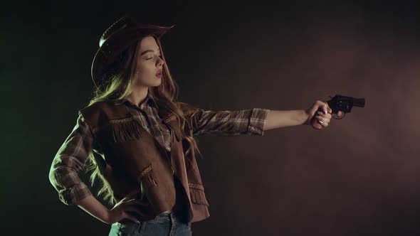 Cowboy Girl Is Aiming and Making a Shot. Black Smoke Background. Slow Motion alt