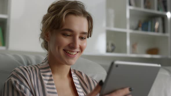 Portrait Smiling Woman Reading Good News Holding Tablet Computer at Home alt