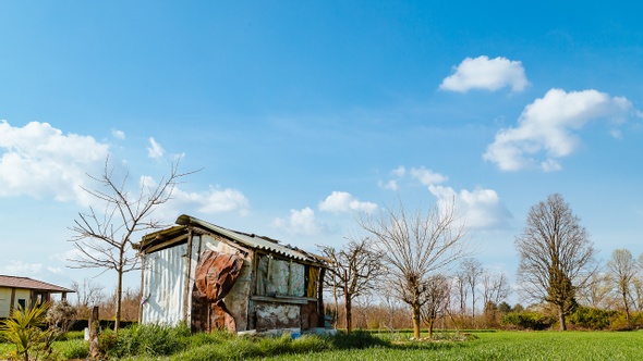 Farmer shack against spring blue sky with white clouds moving, timelapse
