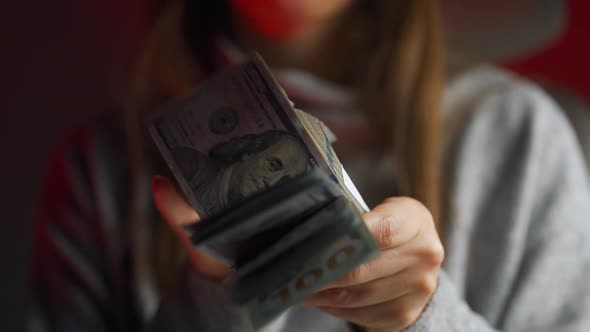 Woman Checks US Dollar Bills or Counting in Cash Against the Backdrop of Police Car Lights alt