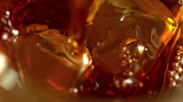 Super Slow Motion Macro Shot of Pouring Whiskey Into Glass with Ice Cubes at 1000Fps alt