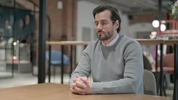 Pensive Young Man Thinking While Sitting in Cafe alt