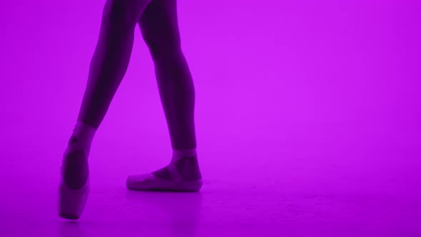 Ballet Dancer's Feet in Pointe Shoes Doing Pas Under Purple Neon Led Light alt