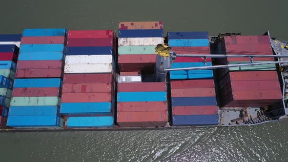 Top down aerial view of a large container ship on a sunny day. Whole ship passes under camera starti alt