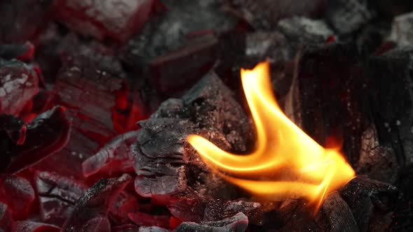 Fire flames over red hot aglow coals in grill alt