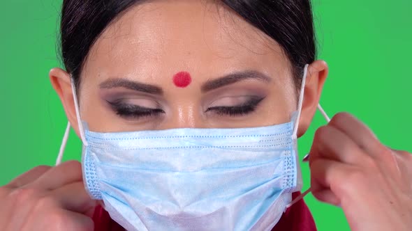 Portrait of Beautiful Indian Girl Is Looking at the Camera and Takes Off Her Protective Medical Mask alt