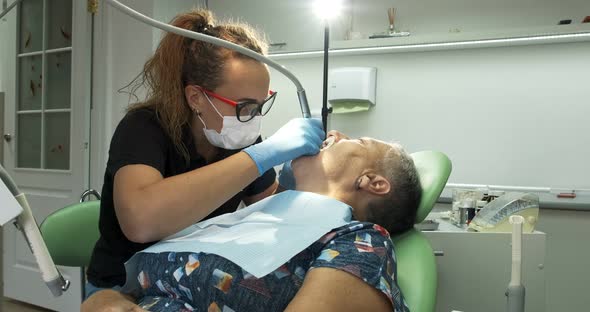 Female Dentist Doing Dental Treatment To Elderly Woman Patient alt