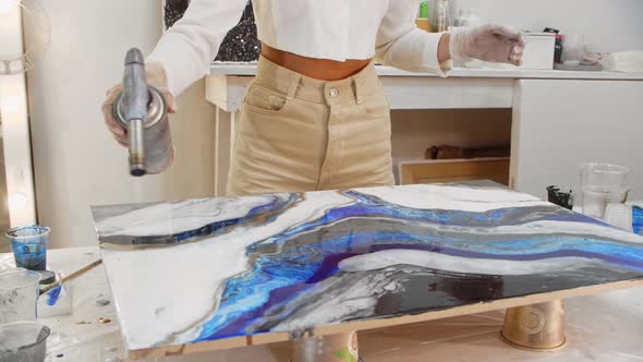 Using a Burner for a Painting Made of Blue Epoxy Resin alt