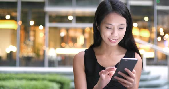 Woman Using cellphone with the background of Hong Kong city  alt