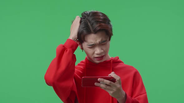 Upset Asian Transgender Male Losing Mobile Phone Game On The Green Screen Background alt