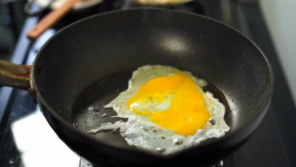 slow-motion of hand cracking egg dropping into a frying pan