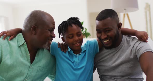 Portrait of african american grandfather, father and son smiling together at home alt