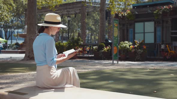 Smiling tourist with a travel book in the park alt