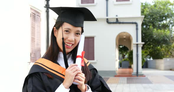 Asian woman wearing graduation gown alt