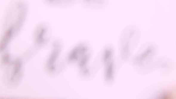 Hand with BE BRAVE card over a wooden table top view alt