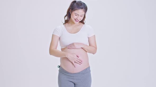 Happy Pregnant Woman standing smile and stroking big belly with love alt