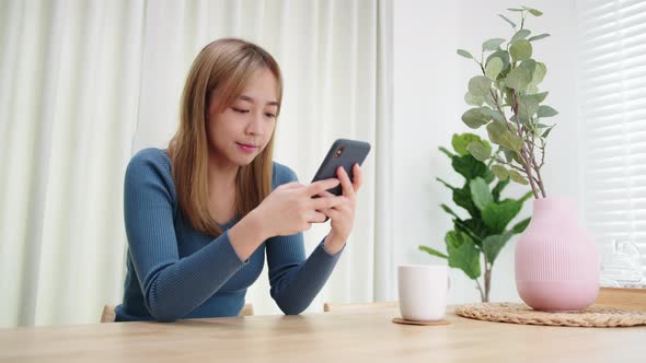 Young Asian Woman using mobile phone enjoying searching, surfing on the internet on a phone