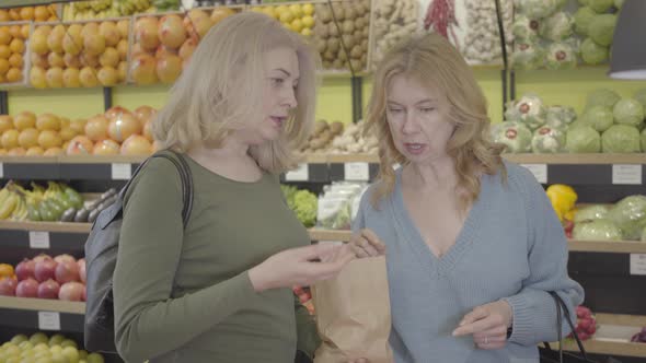 Portrait of Two Confident Caucasian Housewives Discussing Purchases in Grocery Store. Senior Blond alt