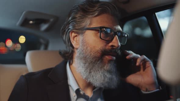 Middle Aged Businessman Talking on Phone while Riding in Taxi alt