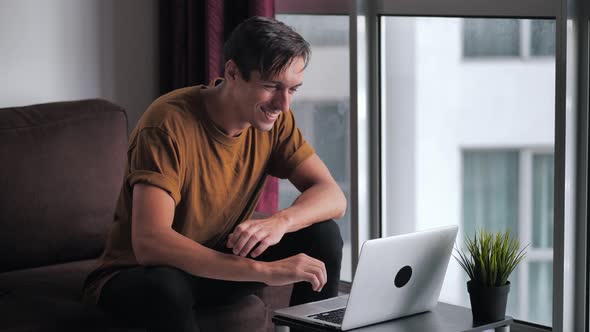 Successful Man Using Laptop Gets Surprised Then Happy and Celebrates Win While Sitting on Sofa at alt