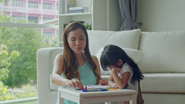 Young mother teaching cute daughter drawing on paper