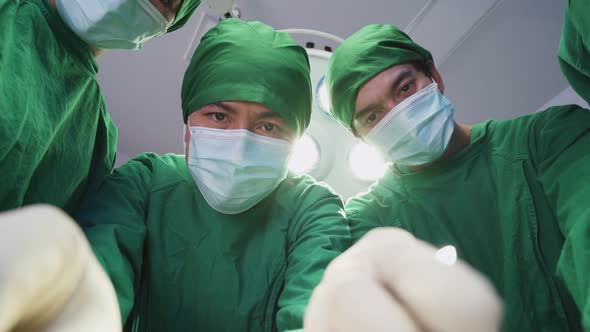 Asian professional medical team performing surgical operation in modern operating room in hospital. alt