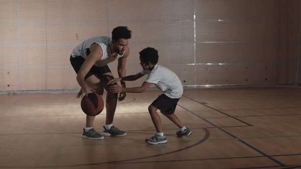 Slowmo of Father and Son Playing Basketball on Indoor Court alt