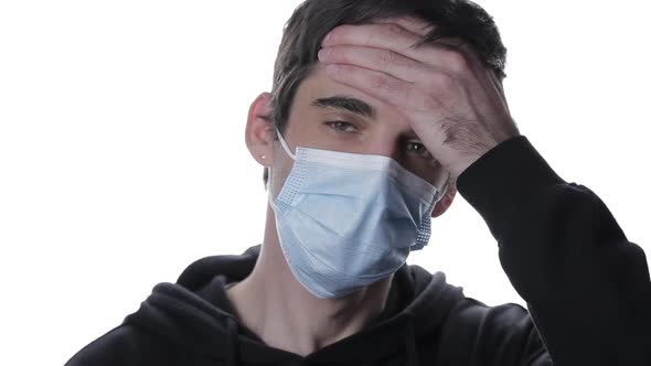 A Portrait of a Young Man in a Medical Mask Looks at the Thermometer and Checks the Temperature of