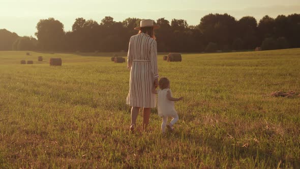 Mom and child walk by the hand across the field