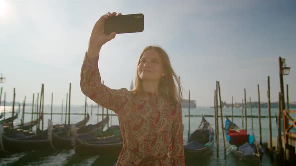 Woman Takes Selfie Photos By Phone with Gondolas in Venice in Italy Europe