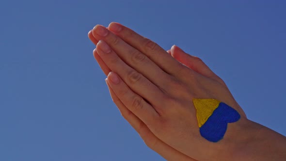 Female Hands in Pray Painted in Ukraine Flag Colors