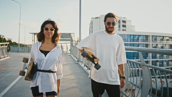 Man and Woman Walking with Skateboard and Talking in City Slow Motion alt