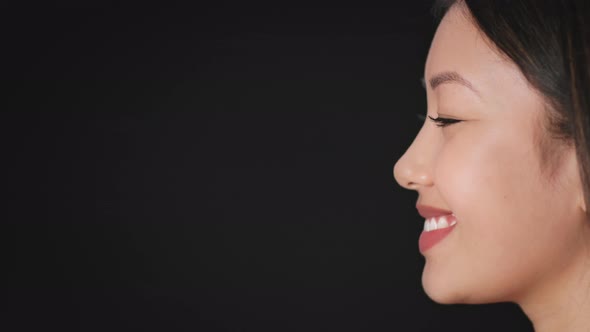 Profile Portrait of Young Asian Lady with Perfect Skin Smiling Looking Aside at Empty Space Over alt
