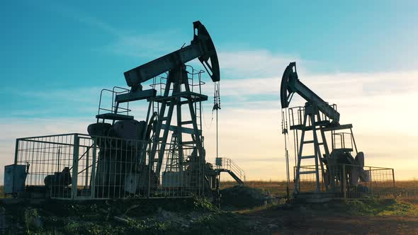 Metal Pumpjacks Are Working at the Oil Extraction Site alt